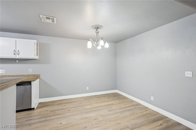 unfurnished dining area featuring light wood-style floors, baseboards, visible vents, and a notable chandelier