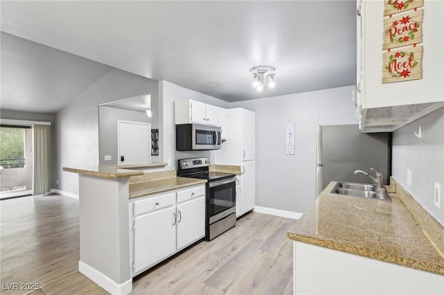 kitchen with stainless steel appliances, a sink, light wood-type flooring, a peninsula, and baseboards