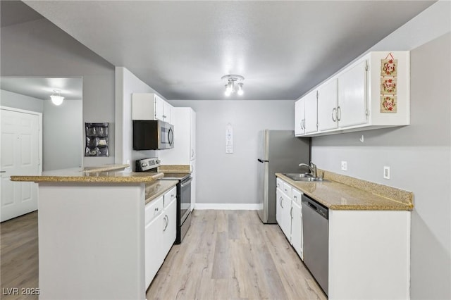 kitchen with light wood finished floors, appliances with stainless steel finishes, a sink, and white cabinets