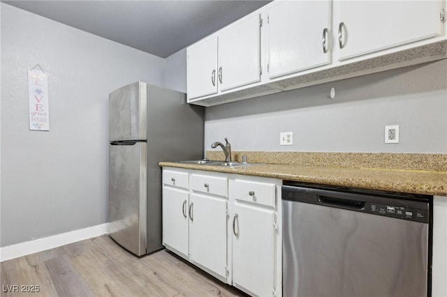 kitchen featuring baseboards, white cabinets, stainless steel appliances, light wood-type flooring, and a sink