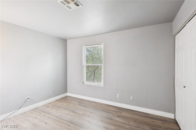 unfurnished bedroom featuring baseboards, visible vents, a closet, and wood finished floors