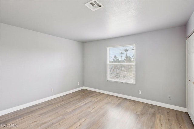 spare room featuring wood finished floors, visible vents, and baseboards