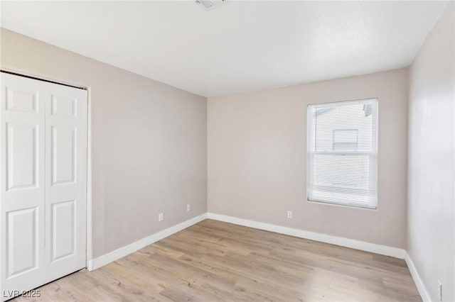 unfurnished bedroom featuring baseboards, a closet, visible vents, and light wood-style floors