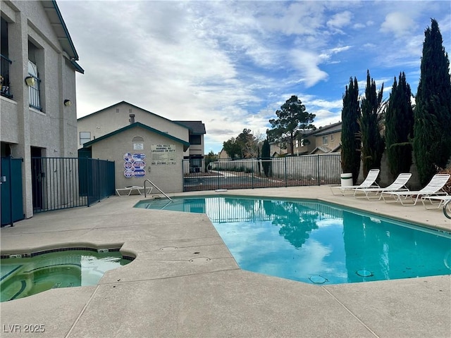 community pool with a patio area, a hot tub, and fence