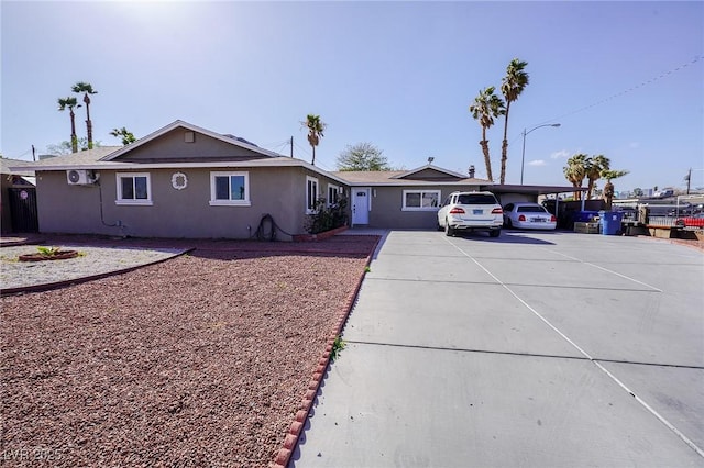 single story home featuring a carport, concrete driveway, and stucco siding