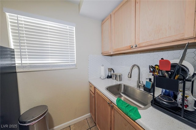 kitchen with tasteful backsplash, light brown cabinets, light countertops, and a sink