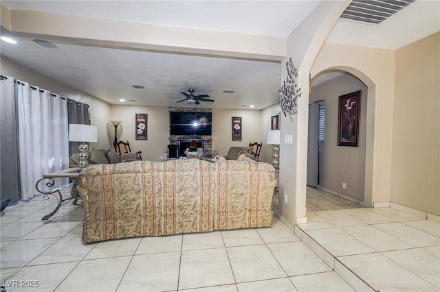 living room featuring arched walkways, ceiling fan, visible vents, and baseboards