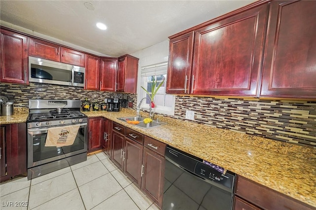 kitchen with light stone countertops, a sink, appliances with stainless steel finishes, decorative backsplash, and reddish brown cabinets