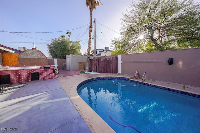 view of swimming pool with a fenced in pool, a fireplace, a patio area, a fenced backyard, and a diving board