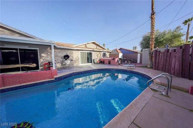 view of pool featuring a fenced in pool, an outbuilding, fence, a patio area, and a diving board