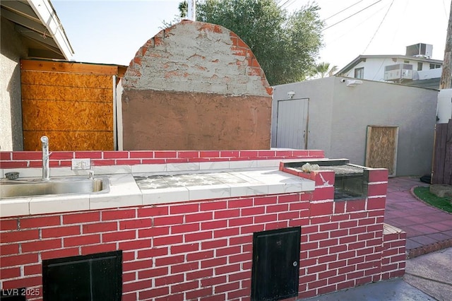 details with cooling unit, brick siding, a sink, and stucco siding