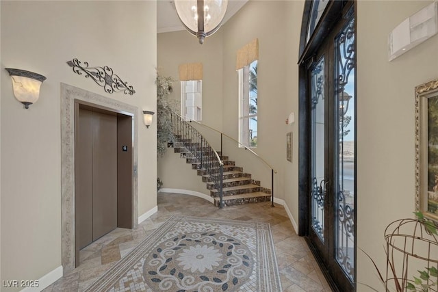 foyer entrance featuring a high ceiling, baseboards, stairs, french doors, and elevator