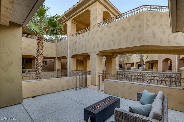 view of patio featuring an outdoor fire pit and a balcony