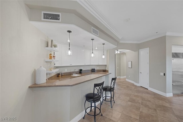 kitchen featuring arched walkways, a sink, visible vents, and white cabinets