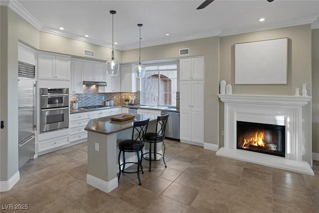 kitchen with stainless steel appliances, visible vents, white cabinetry, a sink, and under cabinet range hood