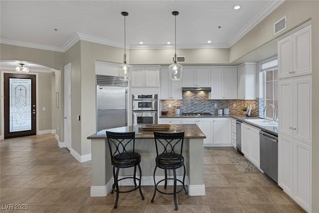 kitchen featuring stainless steel appliances, arched walkways, visible vents, and a sink