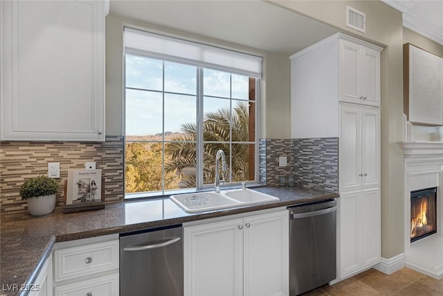 kitchen featuring visible vents, a glass covered fireplace, white cabinetry, a sink, and dishwasher