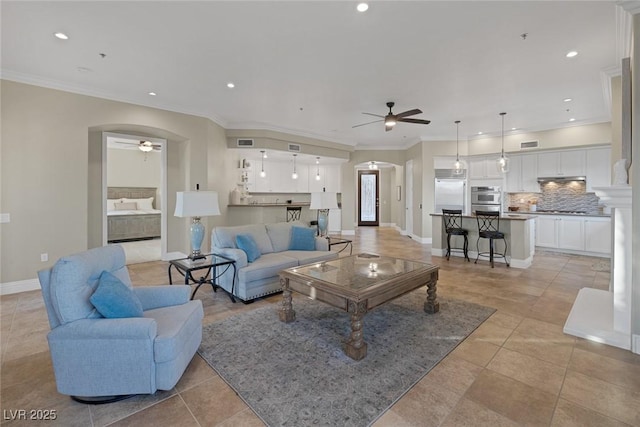 living room with arched walkways, ceiling fan, and crown molding