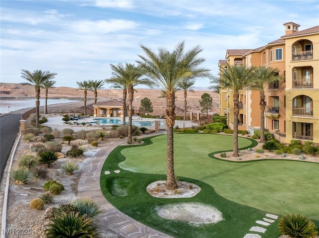 view of community with a swimming pool, a water view, and fence