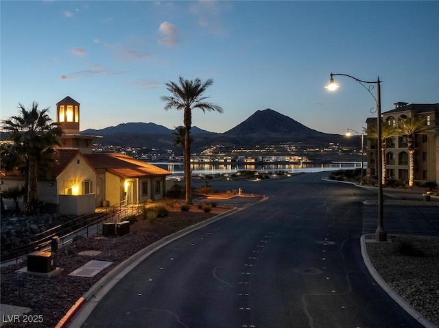 view of street with curbs, a mountain view, and street lights