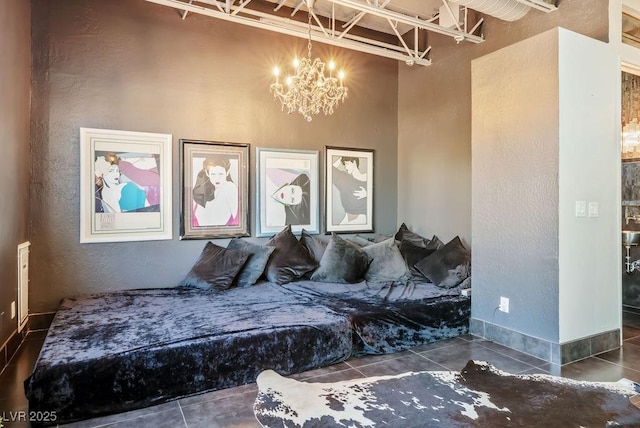 tiled bedroom with a notable chandelier, a textured wall, and baseboards