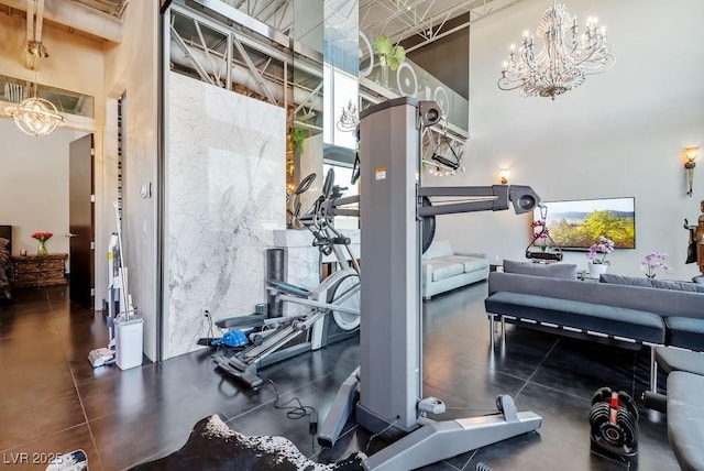 exercise room featuring a chandelier and a towering ceiling