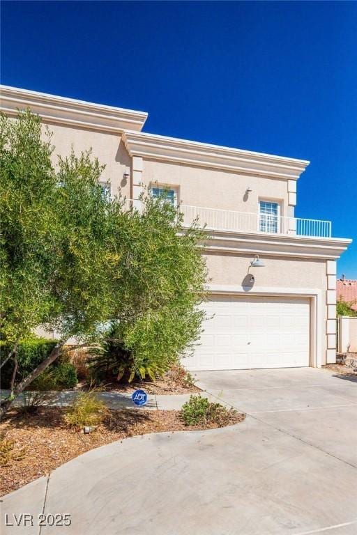 view of front of house with a balcony, driveway, an attached garage, and stucco siding