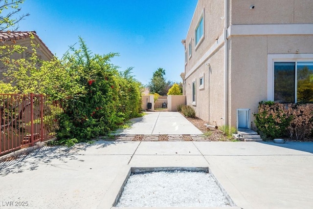 view of side of home with a patio, fence, a gate, and stucco siding