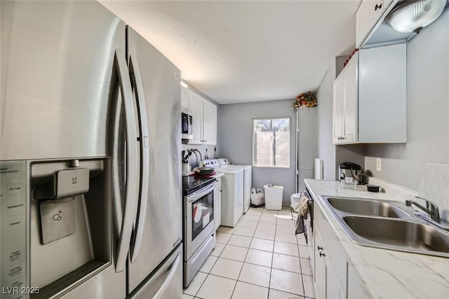 kitchen with appliances with stainless steel finishes, light tile patterned flooring, a sink, and white cabinetry