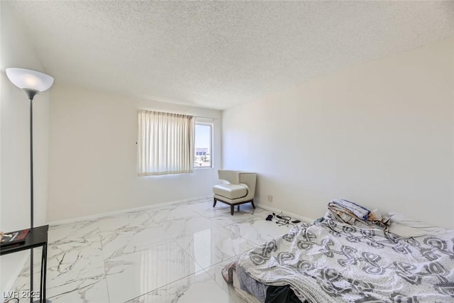 bedroom featuring a textured ceiling, marble finish floor, and baseboards