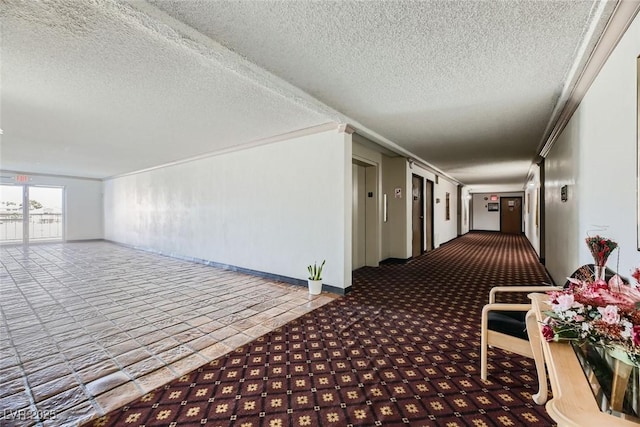 hall with a textured ceiling and ornamental molding