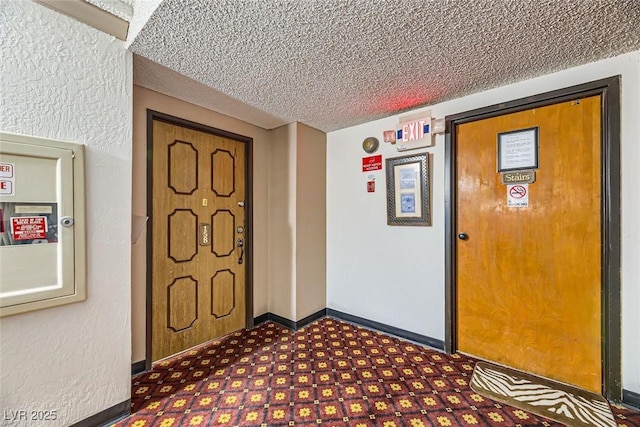 entrance foyer with dark floors, baseboards, and a textured ceiling