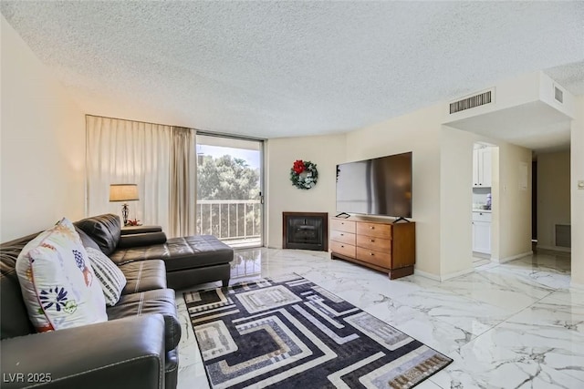 living area featuring marble finish floor, baseboards, visible vents, and a textured ceiling