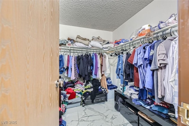 walk in closet featuring marble finish floor