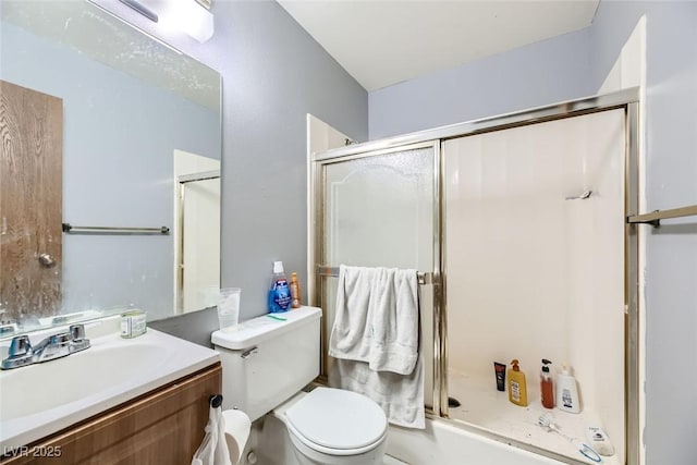 bathroom featuring toilet, a shower with door, and vanity