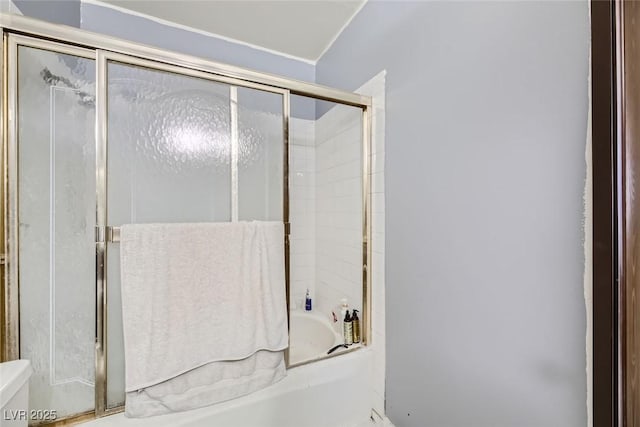 bathroom featuring toilet and combined bath / shower with glass door