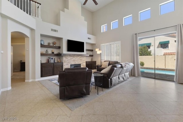 living room with arched walkways, built in shelves, light tile patterned flooring, visible vents, and baseboards