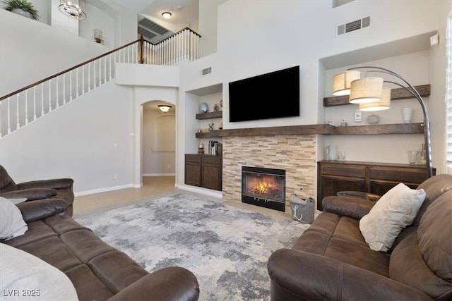 living room with arched walkways, a fireplace, visible vents, and baseboards