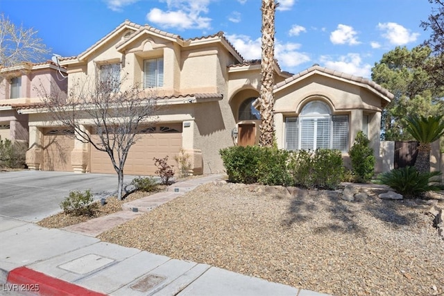 mediterranean / spanish house with a garage, a tiled roof, driveway, and stucco siding