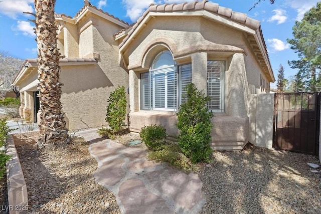 exterior space featuring a tile roof and stucco siding