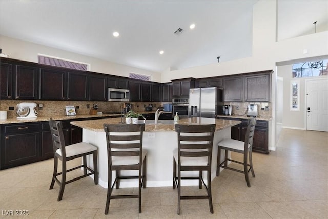 kitchen with appliances with stainless steel finishes, visible vents, backsplash, and a kitchen bar