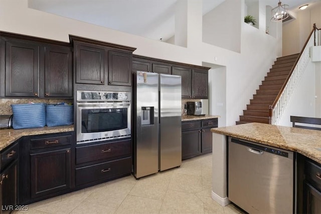 kitchen with light stone counters, light tile patterned floors, tasteful backsplash, appliances with stainless steel finishes, and dark brown cabinetry