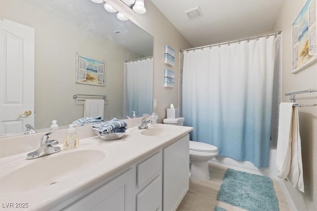 bathroom featuring toilet, double vanity, visible vents, and a sink