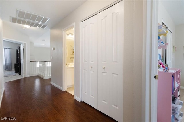 hall featuring visible vents, baseboards, and wood finished floors