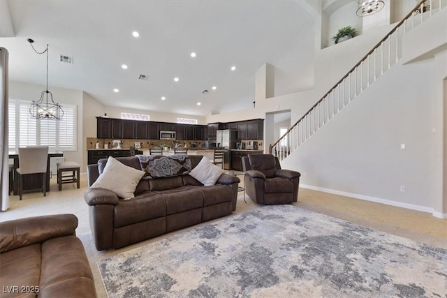 living area with a notable chandelier, recessed lighting, visible vents, a towering ceiling, and stairs