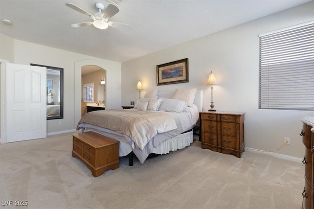 bedroom with arched walkways, light colored carpet, and baseboards