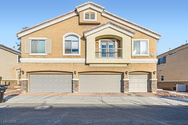 view of front facade with stucco siding, an attached garage, and a tile roof