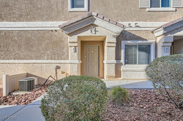 entrance to property with central air condition unit and stucco siding