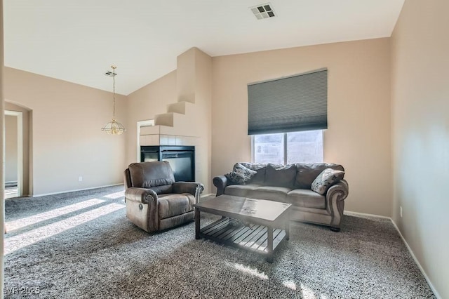 carpeted living area featuring a tiled fireplace, baseboards, visible vents, and high vaulted ceiling