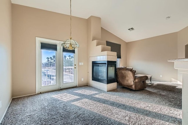 unfurnished living room with a tiled fireplace, carpet flooring, visible vents, and high vaulted ceiling